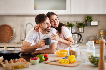 A couple shares a joyful moment in their kitchen, smiling as they prepare breakfast with vibrant...