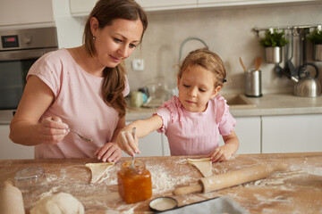 A mother and her daughter share a delightful moment in the kitchen, working together to prepare...