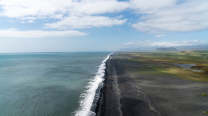 Aerial view of the black sand beach stretching along the Atlantic near Vik, Iceland, shaped by ancient volcanic forces and crashing ocean waves.