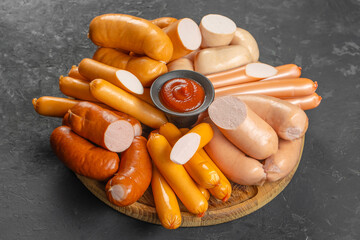 Assorted boiled and smoked sausages of various colors and textures arranged on a wooden platter...