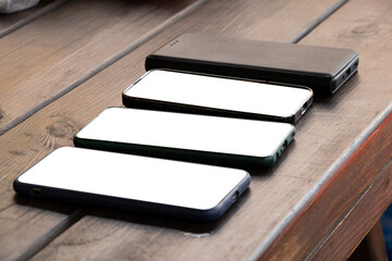 Smartphones with white screens on a wooden table as mockups, templates for design, empty screen,...