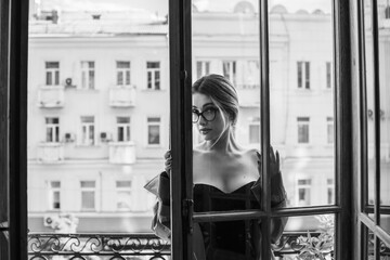 Vintage cinematic look, woman in lingerie and coat at balcony at city background