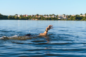 Man drowning in a lake is raising hand for help