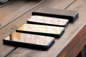 Four different smartphones on a wooden table outdoors, the theme of communication, communication,...