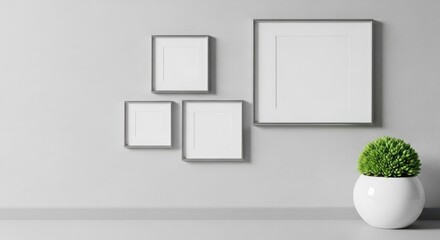 Empty picture frames on a light gray wall with a plant