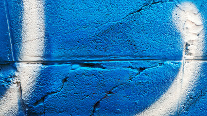 Spray paint on blue brick wall with white lines sprayed on abstract background wall.