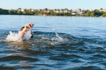 Man drowning in a lake is raising his arm and asking for help