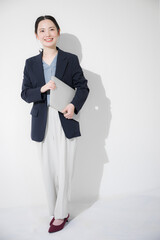 パソコン持って立つ若いかわいい女性のビジネスイメージ全身
