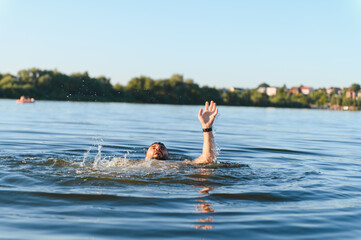 Man drowning in a lake is raising his arm and asking for help