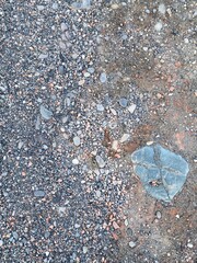 A Closeup View of Various Small Stones and Pebbles Scattered on the Ground with a Larger Rock...