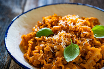Creamy tomato and stracciatella reginelle noodles on wooden table
