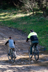 Naklejka premium Father and son enjoy a bike ride on a trail through the woods.