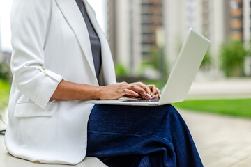 Black woman working on laptop outdoors in a modern urban setting during daytime
