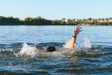 Man drowning in a river is raising his hand asking for help