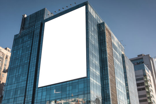 Large blank billboard sits atop a building in a dense urban cityscape during daytime in Asia - Powered by Adobe