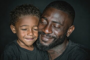Young son cuddles close to his loving father on a black background, showing affection