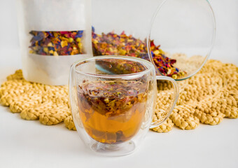 Herbal tea with natural ingredients. Transparent cup of herbal tea with leaves and flowers on a...