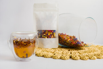 Herbal tea with natural ingredients. Transparent cup of herbal tea with leaves and flowers next to...
