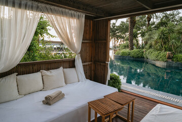 Loungers with white curtains and pool view 