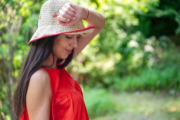 Woman with red dress and straw hat in the summer nature 