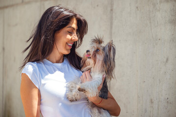 Beautiful woman hugging her yorkie dog outdoor 