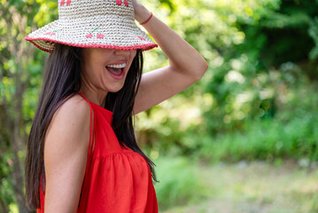 Laughing Woman with red dress and straw hat in the summer nature 
