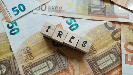 IRES acronym made of wooden letter cubes on pile of Euro banknotes. Imposta sul Reddito delle...