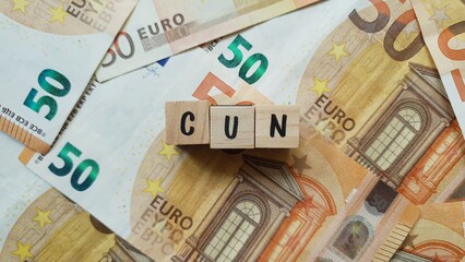 CUN acronym made of wooden letter cubes on pile of Euro banknotes. Contributo Unificato Nazionale...