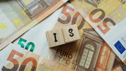 IS acronym made of wooden letter cubes on pile of Euro banknotes. Imposta sulle Società (Corporate...