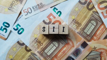 SII acronym made of wooden letter cubes on pile of Euro banknotes. Sistema di Interscambio (Interchange System for invoices in Italy)