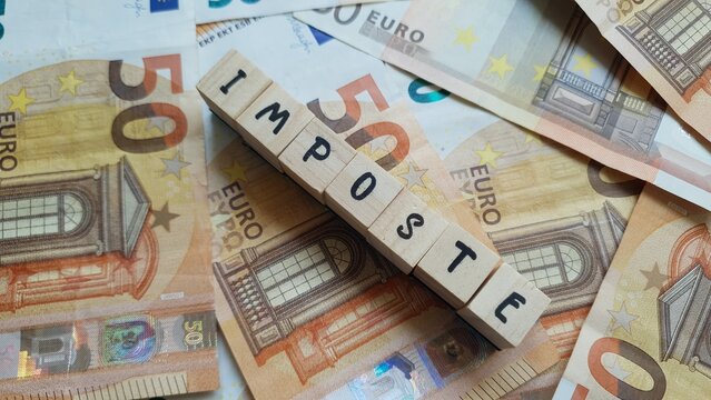 IMPOSTE (Taxes) word made of wooden letter cubes on pile of Euro banknotes