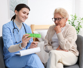 Nurse giving pills to senior woman indoors. Home health care service
