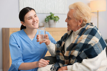 Nurse assisting senior woman indoors. Home health care service