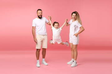 Fototapeta premium Family. Happy parents and their daughter on pink background