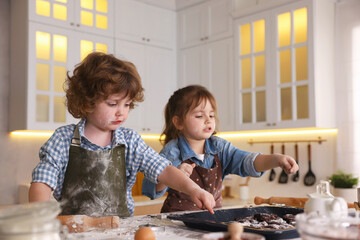 Cooking recipe. Children putting raw cookies onto baking dish at table in kitchen