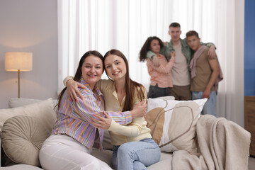 Friends hugging on sofa indoors, selective focus