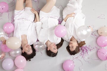 Pajama party. Happy friends with balloons and tinsel on grey background, above view