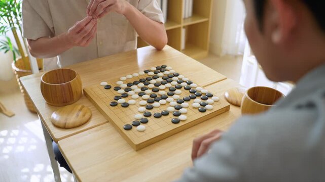 Close up of young men play board game Go during competition in community. 