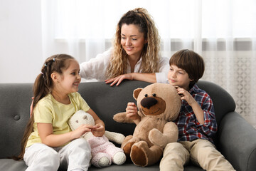 Children and their mother playing with different toys on sofa at home