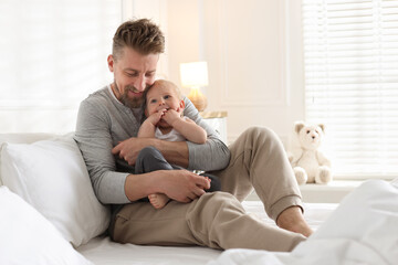 Bedtime. Happy father with his cute little baby on bed at home