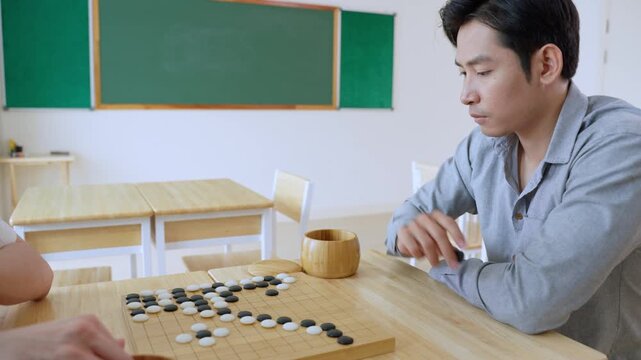 Asian young men playing board game Go during competition in community. 