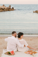 Girl and guy on the beach at sea on a picnic