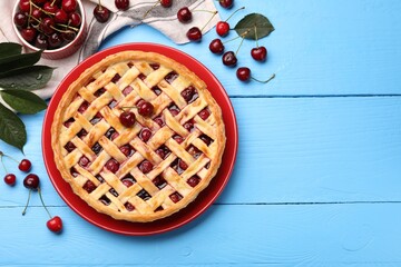 Tasty cherry pie and berries on light blue wooden table, flat lay. Space for text