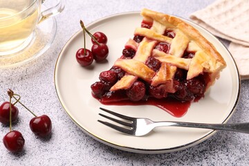 Piece of tasty cherry pie, berries and fork on grey textured table, closeup