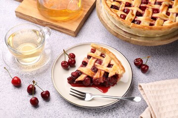 Piece of tasty cherry pie, berries and tea on grey textured table