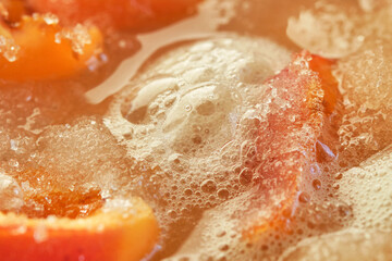 Cooking apricot jam with foam. Orange color apricot berries bubbling in a pot during the simmering process for a fresh homemade jam. Shallow depth of field