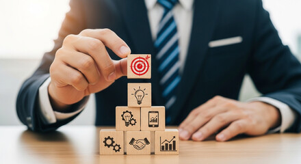 Businessman stacking wooden blocks with business strategy icons on them