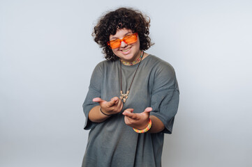 Individual posing playfully in a gray oversized shirt with orange sunglasses, showcasing a vibrant...