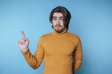 Young man gestures confidently with one finger raised in a vibrant setting with a blue background