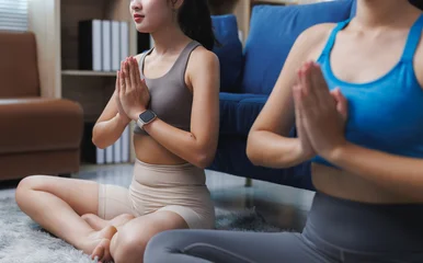 Fotobehang Lotusbloem Women practicing yoga meditation at home in lotus position  © Phimwilai